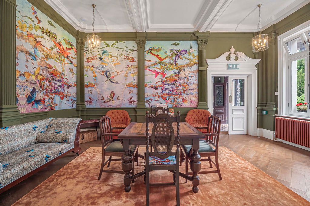 ‘Ariel Dawn Chorus’ wallpaper mural colourful design with birds of paradise, installed in a dentistry waiting room styled with wooden furniture. 