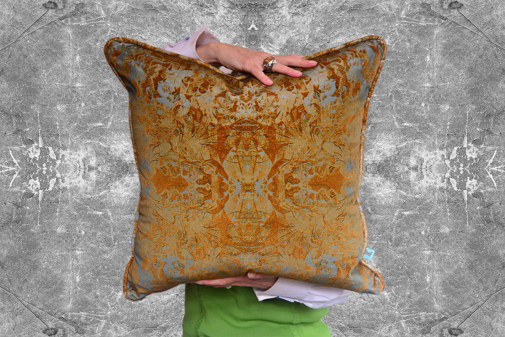 Person holding a Blackpop Garbo velvet cushion with intricate patterns against a textured grey background.