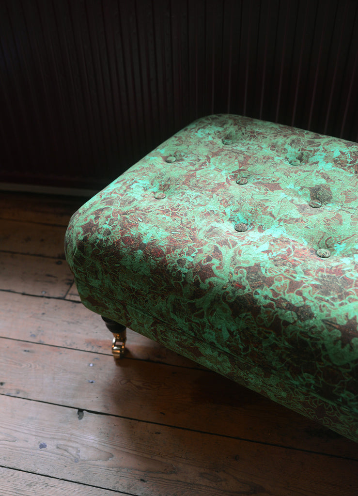 Gatsby damask patterned ottoman on a wooden floor with a dark wall background