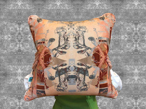 ‘Larson Retro’ square velvet cushion in pink featuring floral and geometric patterns, being held by a person. 