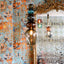 Mary wallpaper featuring abstract geometric designs in orange and teal behind an ornate mirror and a Curiousa glass chandelier. 