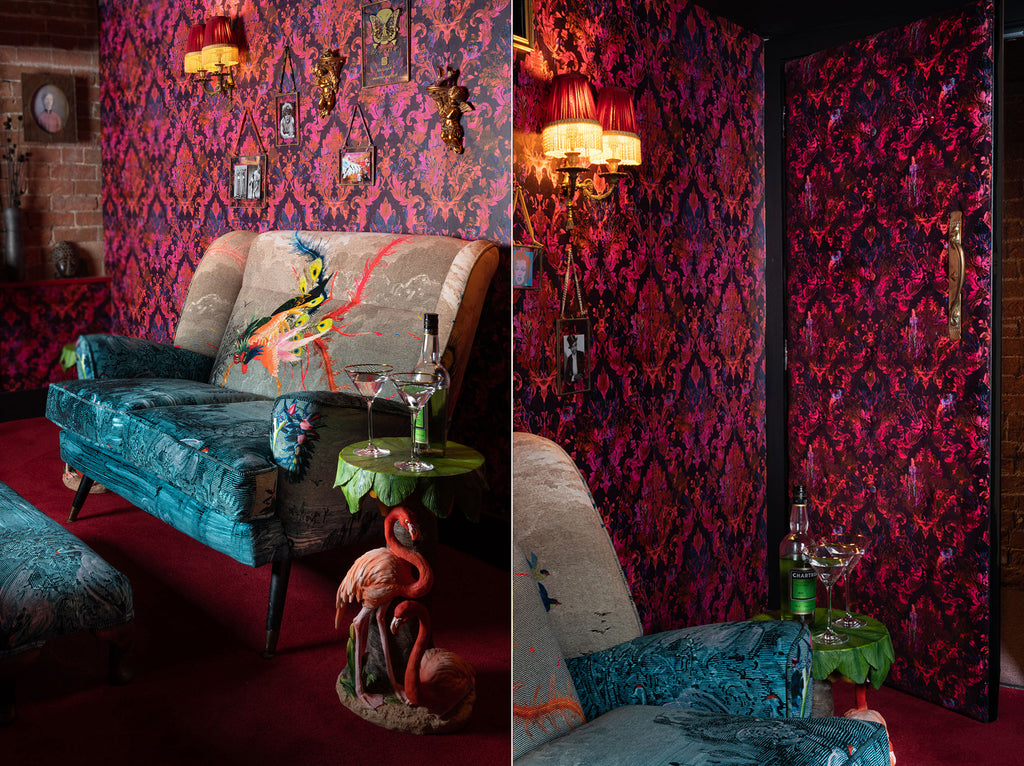 Moulin luxury designer wallpaper with a vibrant damask pattern in shades of pink and red styled behind sofa