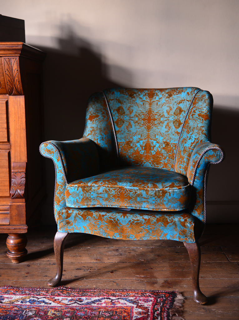 ‘Oscar’ cotton velvet vintage armchair with blue and orange pattern in a dimly lit room.