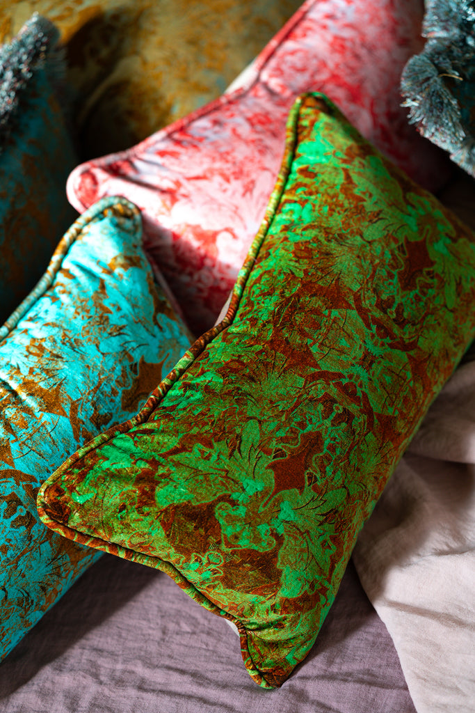 Close-up of Faded Glory collection boudoir cushions with green and red patterns on a textured surface.