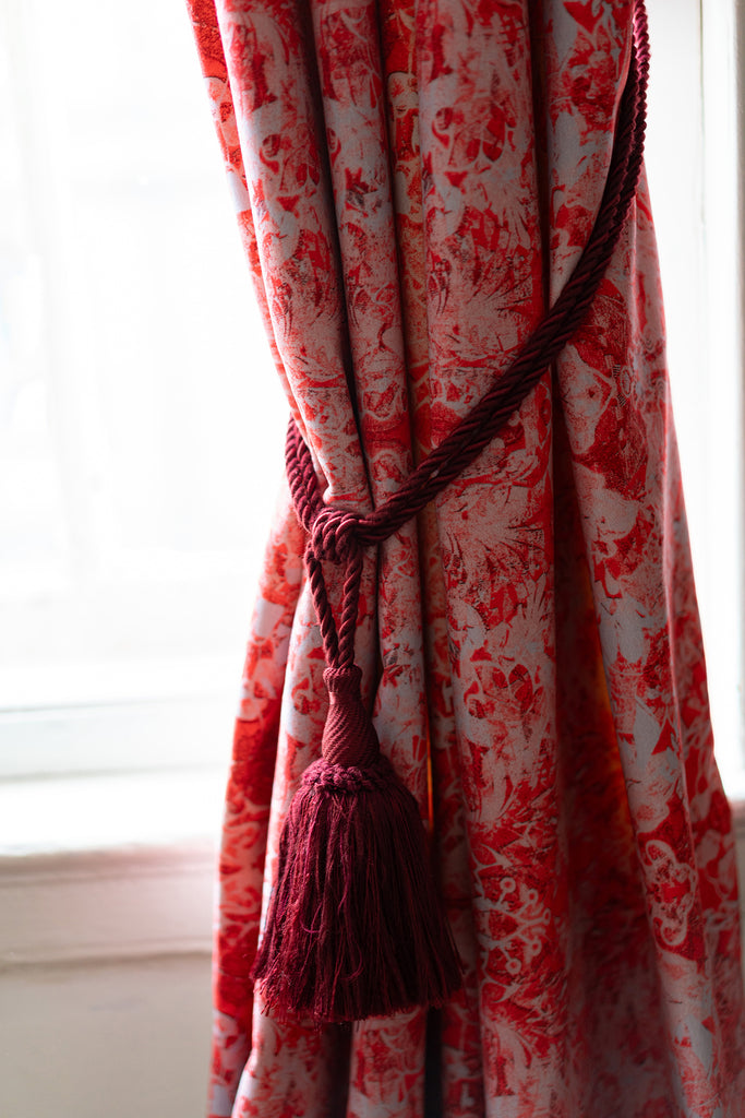 Blackpop Ottoline velvet fabric pink and grey patterned curtain with decorative tieback in front of a window.