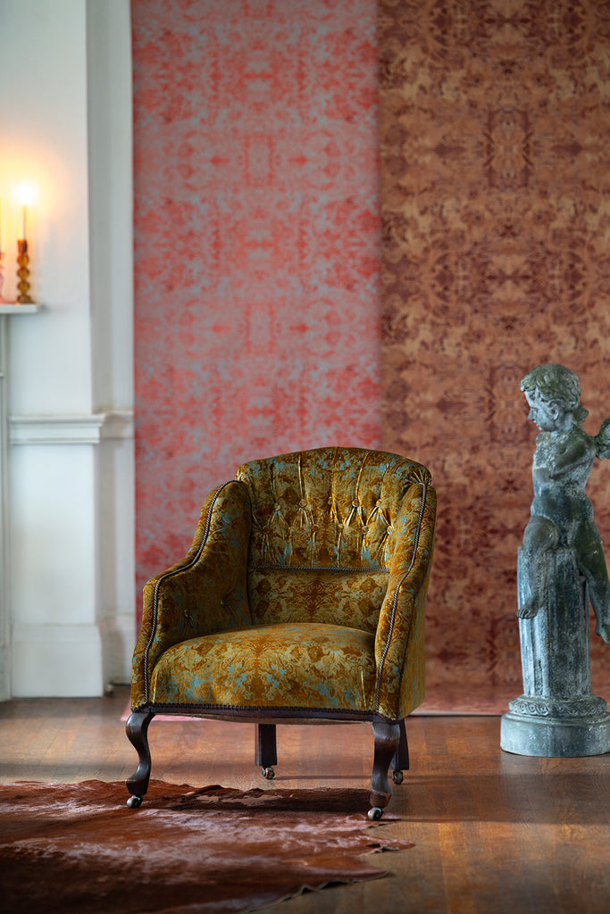 Garbo velvet upholstered armchair in a room with patterned wallpaper and a statue on cowhide rug. 