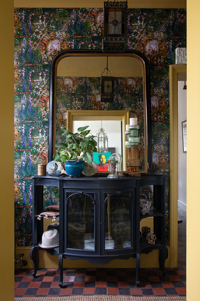 Hampton Hex wallpaper styled in hallway behind mirror and navy cabinet. 
