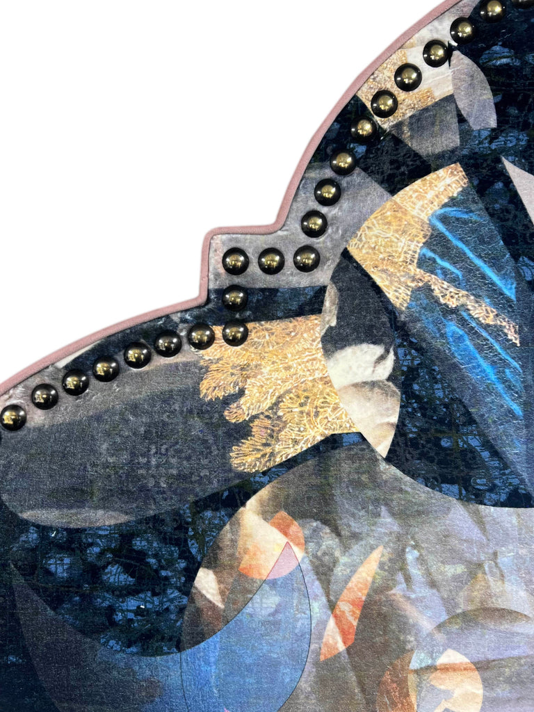 Flat lay detail of ‘Labyrinth’ upholstered headboard featuring navy geometric patterns with dusky piping and gold studs.