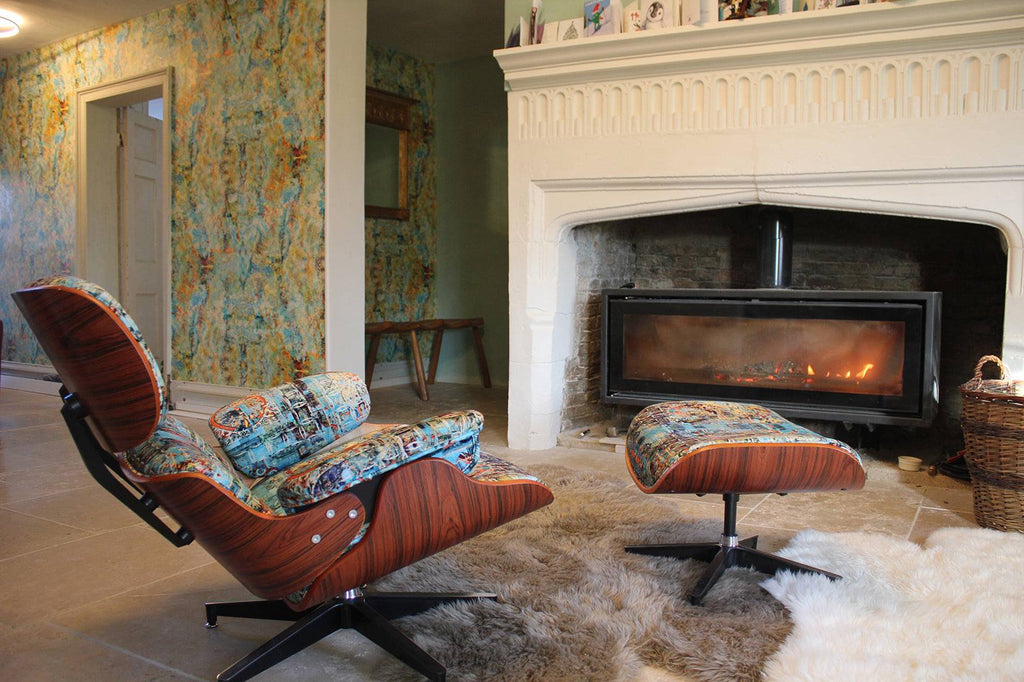 Birdland Jam wallpaper with textured abstract pattern, adding colour to a living room with Eames chair in front of fireplace.