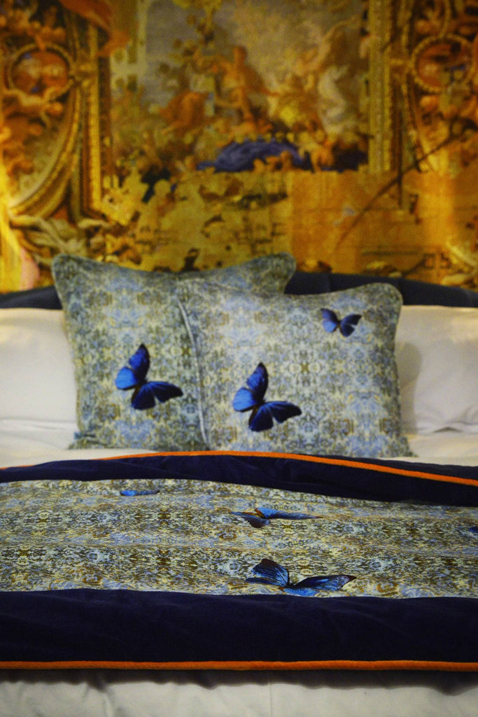 ‘Chapelle Morpho’ velvet cushions and bed throw featuring blue damask pattern and detailed butterflies.