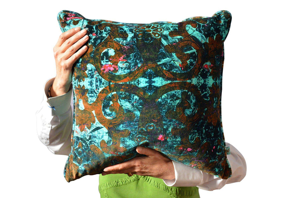Scatter cushion in Dizzy velvet fabric with bold teal and burnt orange design held up by person 