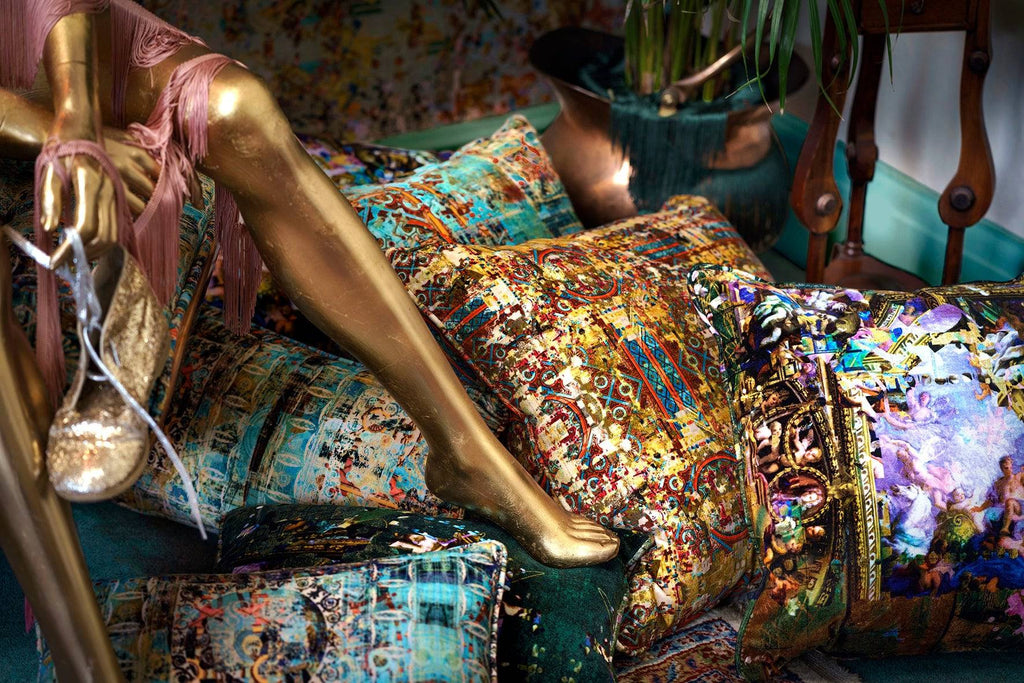 ‘Fresco’ multi coloured velvet square cushion piled next to golden mannequin leg. 